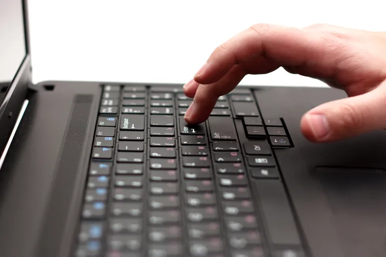 Nærbilde av tastatur og hånd på bærbar PC